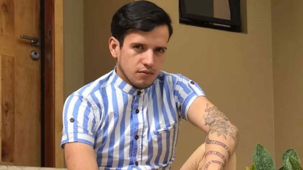 Andry José Hernández Romero seated outdoors in a blue and white striped shirt