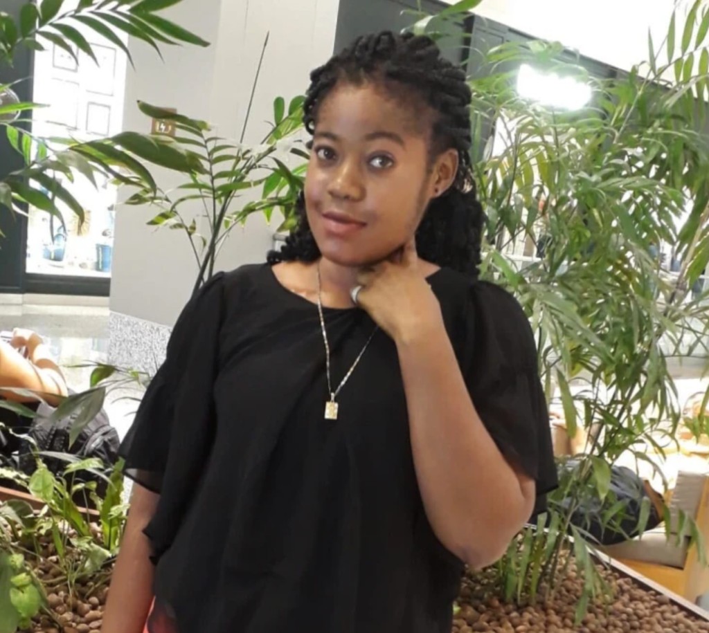 Daphy Michel smiling in a black blouse, with her hand resting at her neck