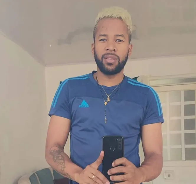 Jerce Reyes Barrios in a mirror selfie wearing a blue Adidas t-shirt and a beaded necklace