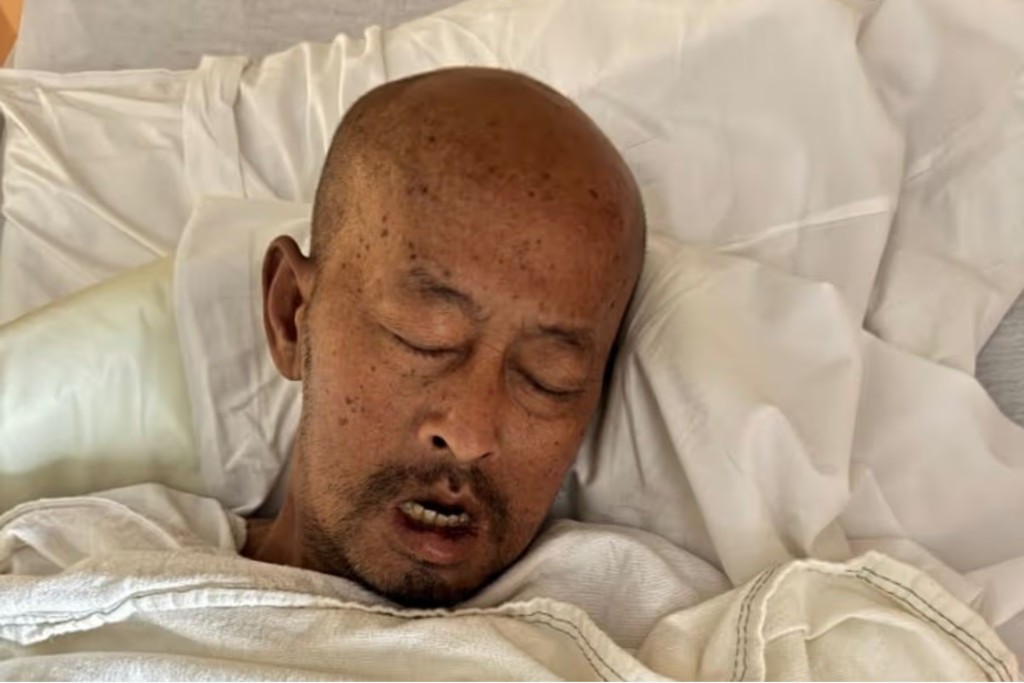 Oudone Lothirath lying in a hospital bed during hospice care